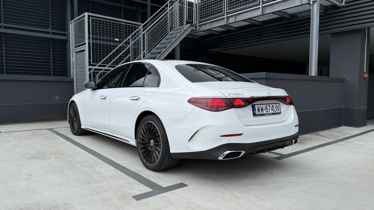 Biały sedan Mercedes-Benz klasy E zaparkowany na parkingu zewnętrznym.