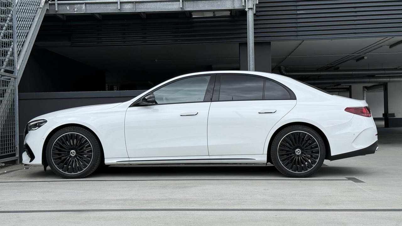 Biały sedan marki Mercedes-Benz z przyciemnionymi szybami i czarnymi felgami na wielopoziomowym parkingu.