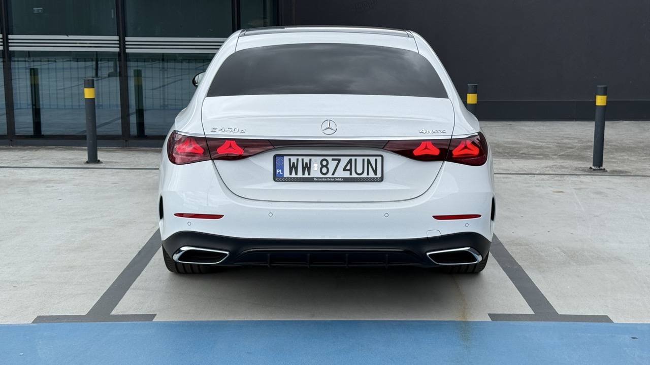 Biały sedan Mercedes-Benz E 450d 4MATIC zaparkowany tyłem na miejscu parkingowym.