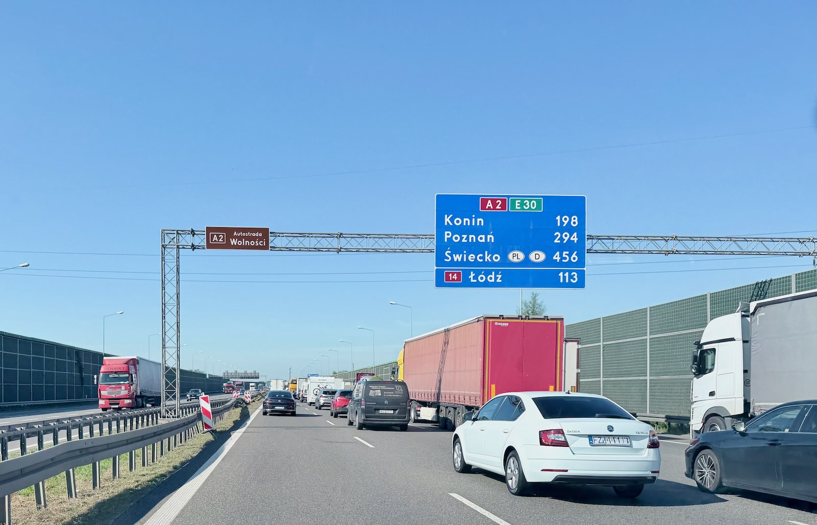 Samochody na autostradzie A2, niebieski znak z odległościami do Konina, Poznania i Łodzi.