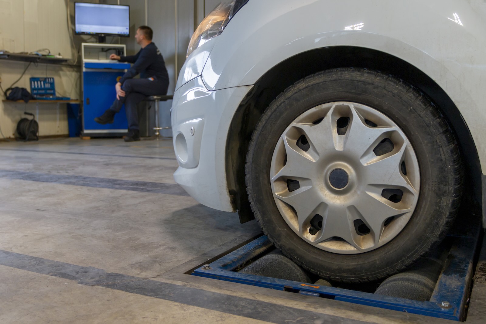 Mechanik sprawdza biały samochód na stacji kontroli pojazdów, gdzie cena przeglądu jest stała.